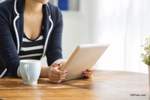 Cropped image of woman using digital tablet while drinking tea